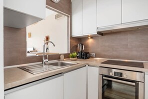 A modern kitchen with a double sink, a built-in oven, and a coffee maker. - Apartment 'Vista Mar y Sol' Estepona (Estepona)