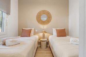 A hotel room with two beds, a round mirror, a lamp, and a small table. - Apartment 'Vista Mar y Sol' Estepona (Estepona)