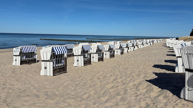 A beach with rows of white beach huts with blue-striped awnings. - "achterhus Usedom" Baltic Sea Idyll in the House on the Water (Zempin)