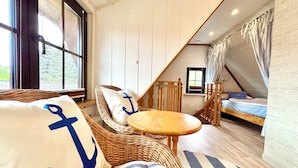 A cozy room with a wicker sofa, a small round table, and a bed with a canopy. - "achterhus Usedom" Baltic Sea Idyll in the House on the Water (Zempin)