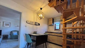 A kitchen with a wooden staircase, a dining area with a table and chairs, and a sign on the wall. - "achterhus Usedom" Baltic Sea Idyll in the House on the Water (Zempin)