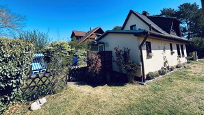 A house with a sloped roof, a small porch, and a fenced yard. - "achterhus Usedom" Baltic Sea Idyll in the House on the Water (Zempin)