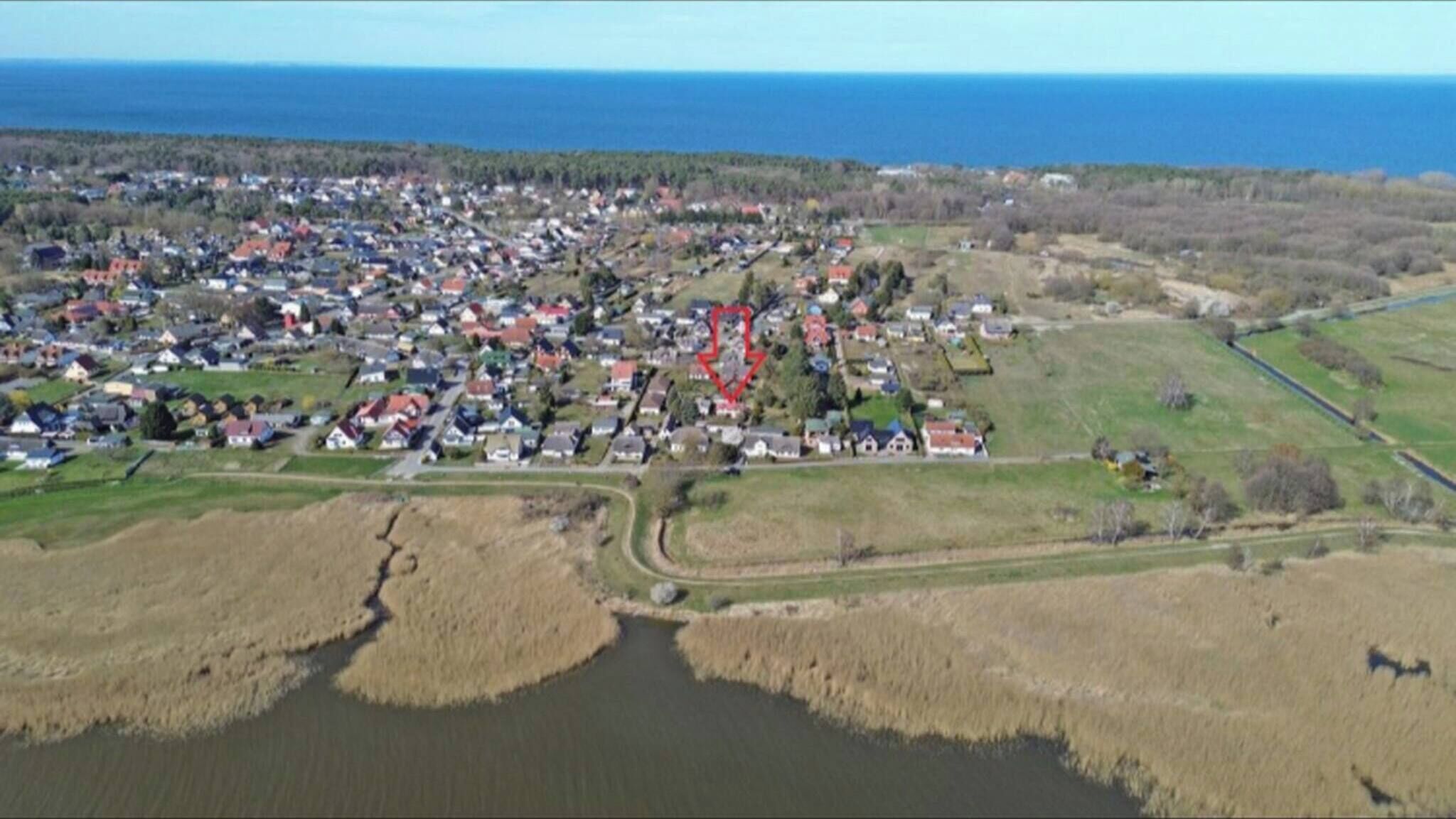 Oversigtsbillede af en kystby med en flod, huse og en vej der fører til havet.