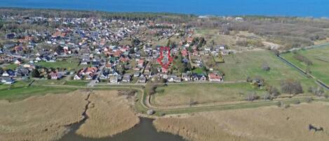 Oversigtsbillede af en kystby med en flod, huse og en vej der fører til havet.
