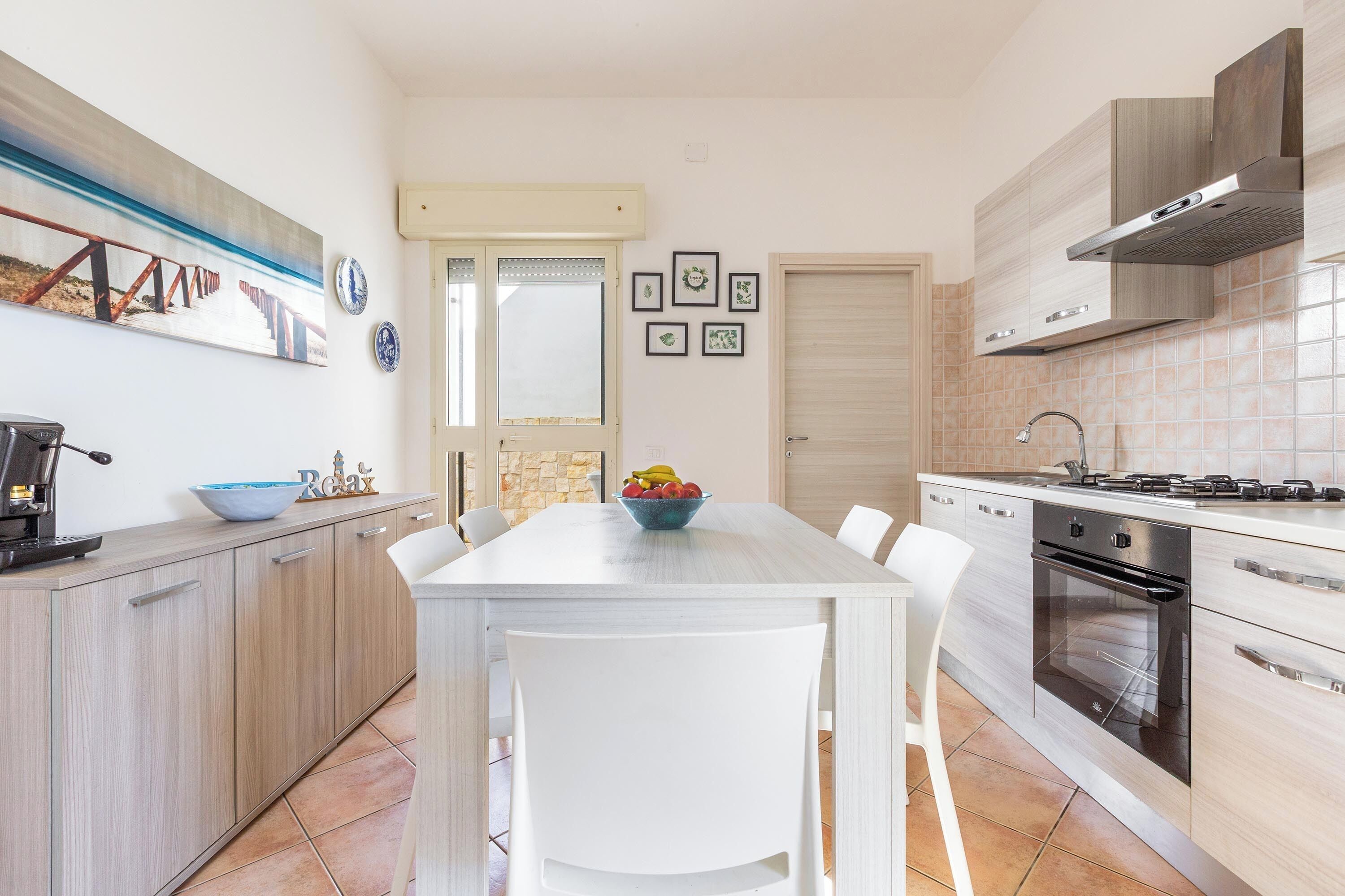 Une cuisine moderne avec une table à manger blanche, un four encastré et une grande fenêtre.