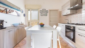 Una cocina moderna con una mesa de comedor blanca, horno empotrado y un ventanal grande.
