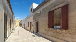 A narrow street lined with buildings, featuring stone facades and wooden shutters. - Acamya by BarbarHouse (Acaya)