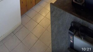 Een keuken met houten kastjes, een koelkast, een koffieapparaat en een hangende kruidenrek.