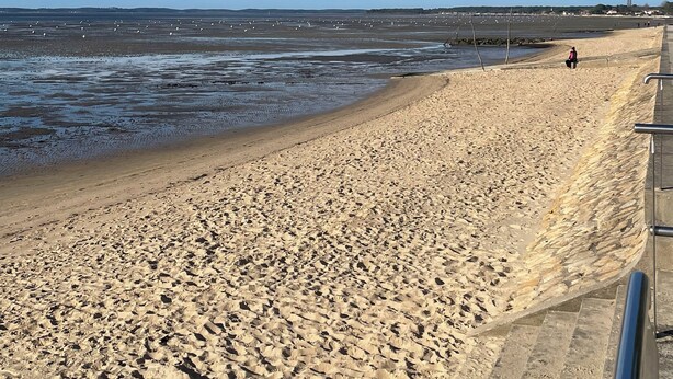 Een zandstrand met een heldere lucht en enkele wolken.