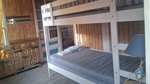 Een slaapkamer met een stapelbed, een houten garderobe en een lamp.