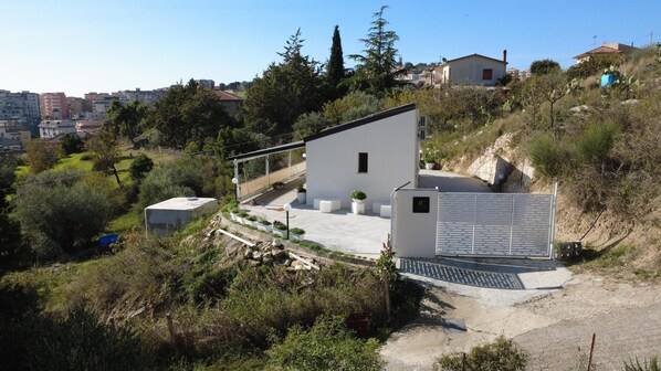 A modern house with a sloped roof, a small attached garage, and a paved driveway. - Comfortable family cottage in the midst of nature (San Cataldo)