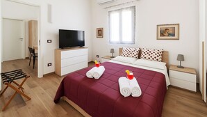 A hotel room with a bed, a TV, a window, and a painting on the wall. - Comfortable family cottage in the midst of nature (San Cataldo)