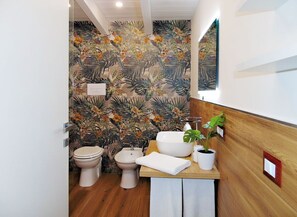 A bathroom with a wooden vanity, a white sink, a bidet, and a toilet. - Comfortable family cottage in the midst of nature (San Cataldo)