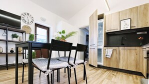 A modern kitchen with wooden cabinets, a dining area with a table and chairs, and a clock on the wall. - Comfortable family cottage in the midst of nature (San Cataldo)