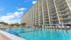 A hotel with a large pool, multiple balconies, and a clear sky. - The Summit 1513 - Your Ultimate Vacation Retreat! (Panama City Beach)