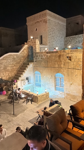 An outdoor seating area with stone walls and a staircase leading to a higher level. - GÖZDE KONAGİ (Mardin)