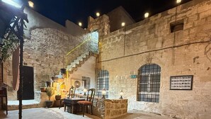 Un patio al aire libre con muros de piedra, una escalera y una zona de estar con mesas y sillas.