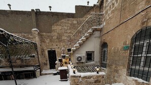 Un patio cubierto de nieve con muros de piedra, una escalera y un banco.