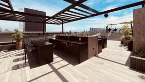 A rooftop bar with a view of the city skyline, outdoor seating, and a pool area. - LM BEACH HAUS (João Pessoa)