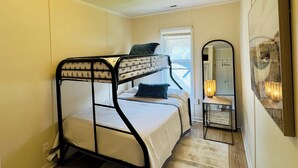 Habitación con literas, una ventana, un espejo y una lámpara.