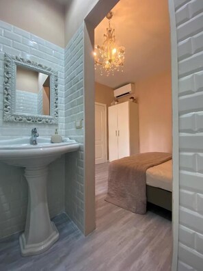 A bathroom with a white sink, a mirror with an ornate frame, and a chandelier. - Alloggio in Pieno Centro a Trento  (Trento)