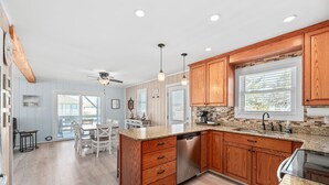 A modern kitchen with wooden cabinets, granite countertops, and a dishwasher. - The Wright Therapy, get your beach medicine here!  NEW LISTING w/ Hot Tub! (Kill Devil Hills)