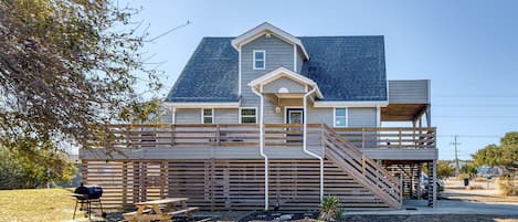 Une maison à deux étages avec une terrasse couverte et un porche à l’avant.
