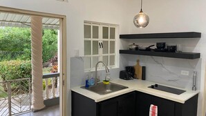 Eine moderne Küche mit schwarzen Schränken, einer weißen Arbeitsplatte, einem eingebauten Backofen und einer hängenden Pendelleuchte.