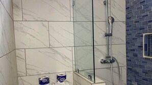 A bathroom with a toilet, a shower, and a glass-enclosed shower area. - Still Point Guesthouse - Premium Two Bedroom (Crown Point)
