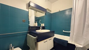 Een badkamer met een wastafel, spiegel en bad.