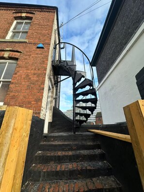 Eine Wendeltreppe führt zu einer zweiten Etage, neben einem Backsteinhaus mit weißer Fassade und einer Garagentür.