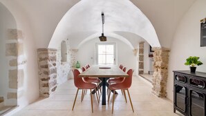 A dining area with a long table, red chairs, and a stone wall. - Authentic house and private spa for 18 people (La Baume-de-Transit)