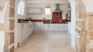 A kitchen with white cabinets, a red backsplash, and a stone archway. - Authentic house and private spa for 18 people (La Baume-de-Transit)