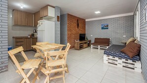 Un espacio habitable compacto con cocina, comedor y una pequeña zona de estar con sofá y cama.