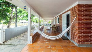 Un patio cubierto con una hamaca, paredes de ladrillo y suelo de baldosas.