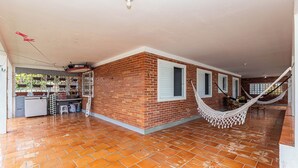 Una habitación amplia con pared de ladrillo, una hamaca y piso de baldosas.