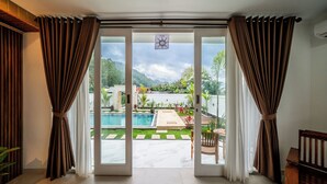 A room with a large sliding glass door leading to an outdoor pool area with a view of a mountainous landscape. - Hayana Villa Kintamani (Kintamani)