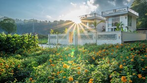 A modern house with a balcony, surrounded by a garden with orange flowers, and a clear sky. - Hayana Villa Kintamani (Kintamani)