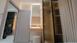 Un baño moderno con cabina de ducha de vidrio, tocador empotrado con espejo y una planta en maceta.