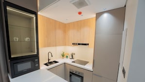 Cocina compacta con microondas, horno, lavaplatos y refrigerador.