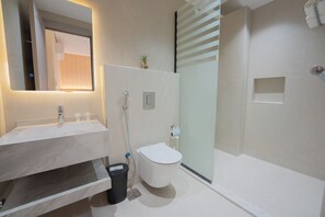 Un baño moderno con lavamanos de mármol, inodoro y ducha con mampara de vidrio.
