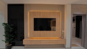 Una sala de estar moderna con televisor integrado, paneles de madera y un pequeño banco.