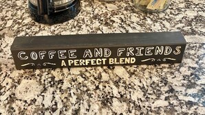 Une machine à café, deux bocaux en verre étiquetés « Crème » et « Sucre », et une pancarte sur laquelle on peut lire : « Café et amis, un mélange parfait ».
