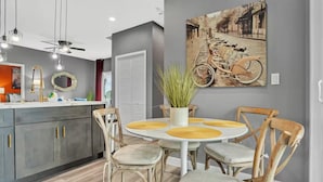 Eine moderne Küche mit grauen Schränken, einem weißen Esstisch mit gelben Platzsets und einem Vintage-Fahrradbild an der Wand.