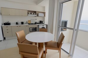 Een moderne keuken met een ronde eettafel en stoelen, een inbouwoven en uitzicht door een glazen deur.