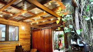 Interior de una cabaña de madera con un banco, una mesa y un gran tronco de árbol.