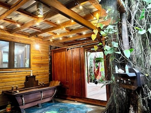 Interior de una cabaña de madera con un banco, una mesa y un gran tronco de árbol.