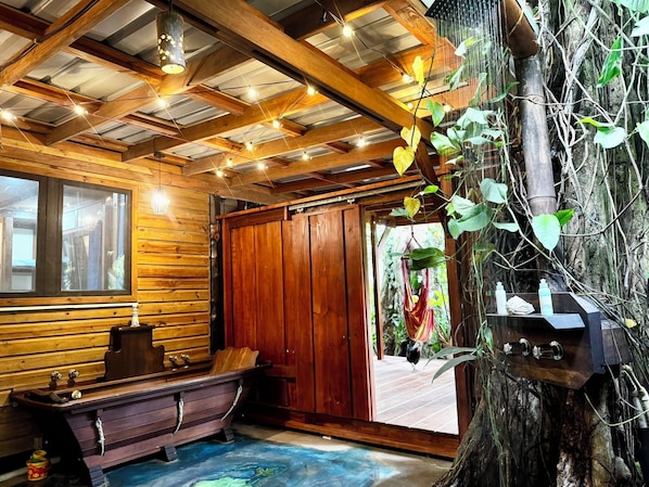 A wooden cabin interior with a wooden bench, a table, and a large tree trunk.
