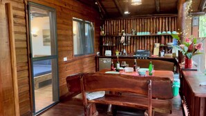 Un interior de madera con una mesa de comedor, sillas y una zona de cocina con una parrilla.