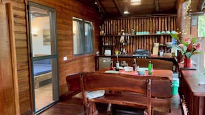 Un interior de madera con una mesa de comedor, sillas y una zona de cocina con una parrilla.
